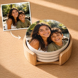 May include: A stack of round ceramic coasters featuring a printed photograph of a smiling young woman and a boy outdoors. The coasters are housed in a light-coloured wooden holder, displaying the same image as the reference photo shown above.