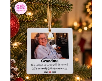 May include: A square white hanging ornament featuring a photograph of an elderly person. Below the photo, the text reads: Grandma, You filled our lives with love and left our hearts full of memories, 1941, a red heart icon, and 2026.