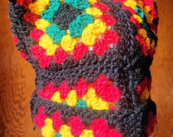May include: A crocheted hat with a black, red, yellow, and green geometric pattern.