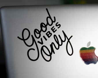 May include: A silver laptop with a black sticker that says "Good Vibes Only" and a rainbow Apple logo.