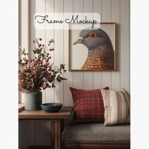 May include: A framed illustration of a gray and brown bird with a red eye. The frame is gold and the illustration is on a white background. The frame is hanging on a white wall with wood paneling. There is a wooden table with a gray vase and a dark gray bowl on it. A gray couch with red and white striped pillows is in the background.