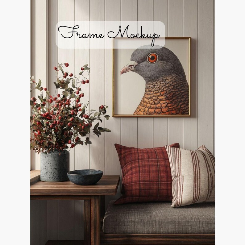 May include: A framed illustration of a gray and brown bird with a red eye. The frame is gold and the illustration is on a white background. The frame is hanging on a white wall with wood paneling. There is a wooden table with a gray vase and a dark gray bowl on it. A gray couch with red and white striped pillows is in the background.