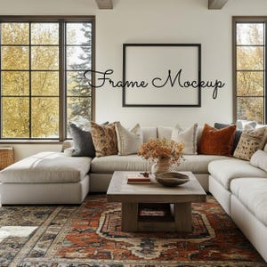 May include: A living room with a large sectional sofa, a wooden coffee table, and a patterned rug. The room has large windows with a view of trees. A black frame is on the wall with the text "Frame Mockup".