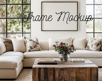 May include: A living room scene with a white sectional sofa, scatter cushions, and a rustic wooden coffee table. A black framed blank canvas hangs on the wall. The image includes the text "Frame Mockup".