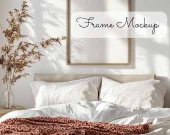 May include: A white bed with a red and white patterned throw blanket. A gold frame with a white background hangs on the wall above the bed. The text "Frame Mockup" is written in black cursive on the wall.