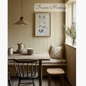 Puede incluir: Un retrato de un caballo blanco en un marco de madera cuelga de una pared beige claro en un comedor. La habitación cuenta con una mesa de madera con sillas, un banco con un cojín de estampado floral y un jarrón de flores secas en un alféizar de ventana.