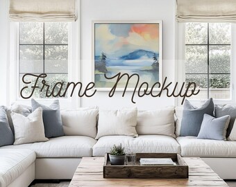 May include: A living room scene featuring a white sectional sofa with various throw pillows in shades of white and blue. A wooden coffee table with a tray and decor sits in front of the sofa. A framed painting hangs on the wall, and the text "Frame Mockup" is displayed.
