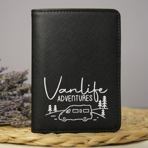 Könnte beinhalten: Schwarzer Reisepass-Etui mit einem weißen Design eines Wohnmobils, Bäumen und dem Text "Vanlife Adventures".