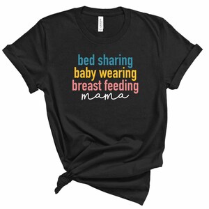 以下が含まれることがあります： カラフルな文字で「bed sharing baby wearing breast feeding mama」と書かれた黒いTシャツです。