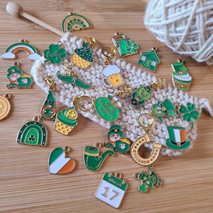 May include: A collection of 18 gold and green enamel charms with St. Patrick's Day themes. The charms include a shamrock, a pot of gold, a leprechaun, a horseshoe, a pipe, a rainbow, a beer mug, a cupcake, a house, a hat, a calendar, and a clover.