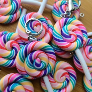 May include: A group of colorful rainbow swirl lollipop keychains. Each keychain features a white stick and a silver ring.