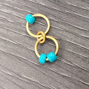 May include: Two gold jump rings connected together with turquoise beads.