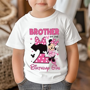 Puede incluir: Camiseta blanca con un dise&ntilde;o de Minnie Mouse rosa y negro. La camiseta presenta el texto "BROTHER of the BIRTHAY GIRL" y un gran n&uacute;mero "2" con lunares rosas. Minnie Mouse lleva un vestido de lunares rosas.