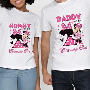 Puede incluir: Camisetas blancas con gr&aacute;ficos de Minnie Mouse. Una camiseta dice "Mam&aacute; de la cumplea&ntilde;era" y la otra "Pap&aacute; de la cumplea&ntilde;era". Ambas camisetas presentan un n&uacute;mero 2 rosa y Minnie Mouse.