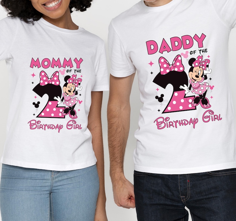 Puede incluir: Camisetas blancas con gr&aacute;ficos de Minnie Mouse. Una camiseta dice "Mam&aacute; de la cumplea&ntilde;era" y la otra "Pap&aacute; de la cumplea&ntilde;era". Ambas camisetas presentan un n&uacute;mero 2 rosa y Minnie Mouse.