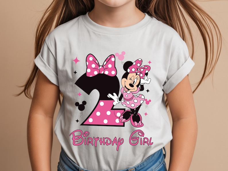 Puede incluir: Camiseta gris claro con un gr&aacute;fico de Minnie Mouse. El dise&ntilde;o incluye un gran n&uacute;mero 2 rosa con lunares blancos, un lazo rosa y las palabras "Birthday Girl" en escritura rosa.