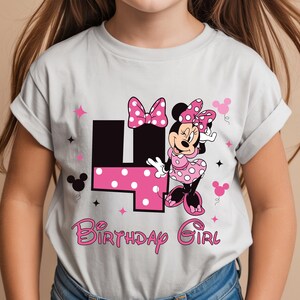 May include: A light grey t-shirt with a Minnie Mouse graphic. The design includes a pink polka dot bow, dress, and the number 4 in black with pink polka dots. The text "Birthday Girl" is in pink.