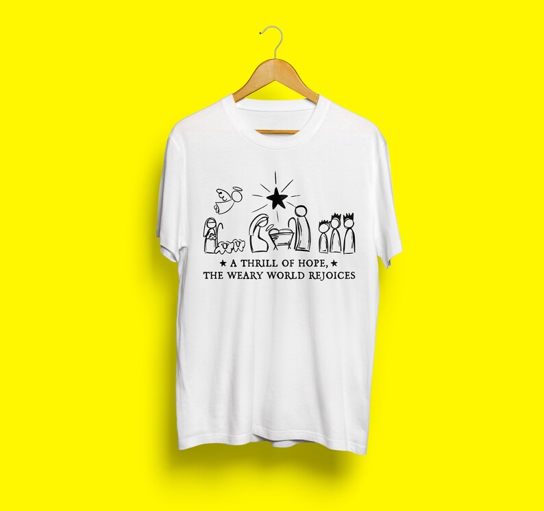 May include: White t-shirt with a black and white illustration of the nativity scene. The text reads "A thrill of hope, the weary world rejoices."
