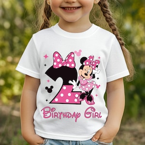 Puede incluir: Camiseta blanca con un dise&ntilde;o de Minnie Mouse para un segundo cumplea&ntilde;os. El dise&ntilde;o incluye un gran lazo rosa con lunares, el n&uacute;mero 2 en rosa con lunares y las palabras "Birthday Girl" en escritura rosa. La camiseta es para un ni&ntilde;o.