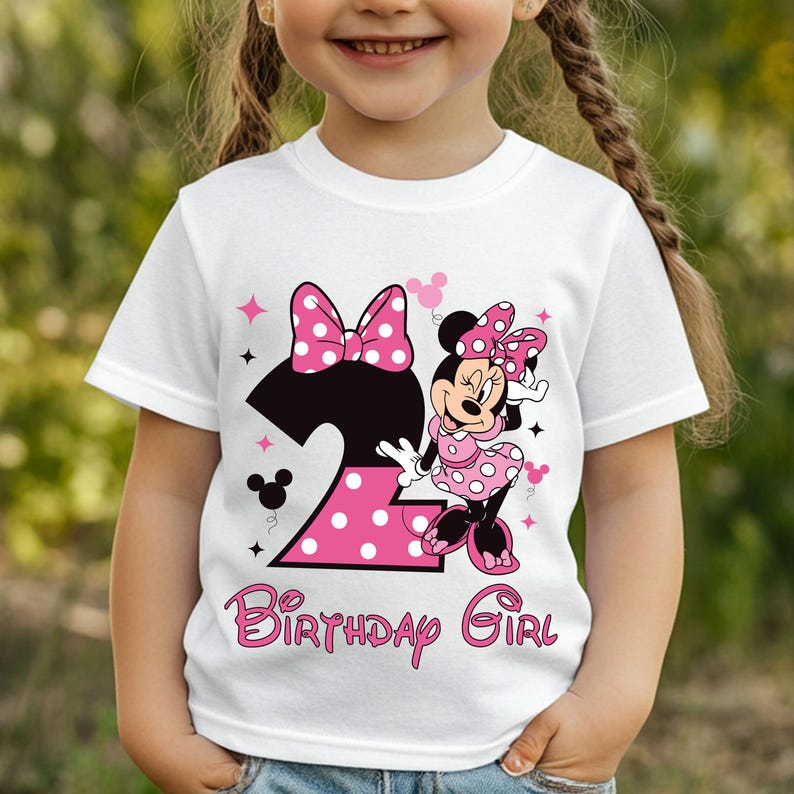 Puede incluir: Camiseta blanca con un dise&ntilde;o de Minnie Mouse para un segundo cumplea&ntilde;os. El dise&ntilde;o incluye un gran lazo rosa con lunares, el n&uacute;mero 2 en rosa con lunares y las palabras "Birthday Girl" en escritura rosa. La camiseta es para un ni&ntilde;o.