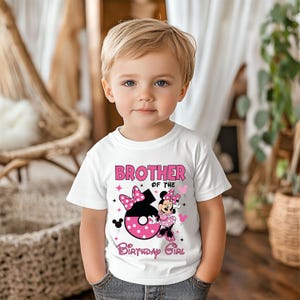 May include: White t-shirt with the text "BROTHER OF THE BIRTHDAY GIRL" in pink. The shirt features a Minnie Mouse graphic with a large number 6. The design includes pink polka dots and stars.