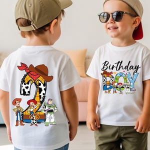 May include: White t-shirts with colorful Toy Story graphics. One shirt features a large number "2" with a cowboy hat and bandana, and Toy Story characters. The other shirt says "Birthday BOY" with Toy Story characters.