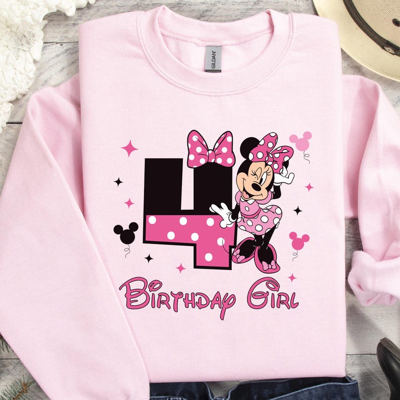 May include: Pale pink sweatshirt with a Minnie Mouse design. The graphic includes a large number 4 with polka dots, Minnie Mouse, and the words "Birthday Girl" in pink. The sweatshirt has long sleeves and a crew neck.