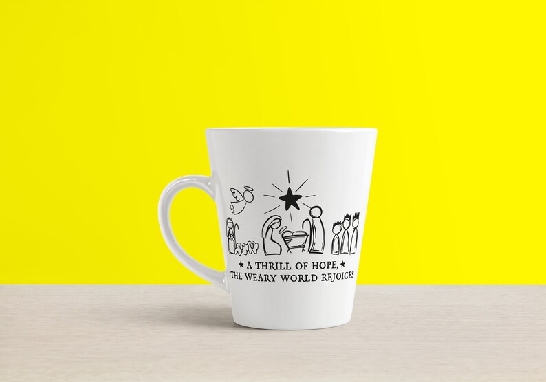 May include: White ceramic mug with a black and white illustration of the nativity scene. The text reads "A thrill of hope, the weary world rejoices."