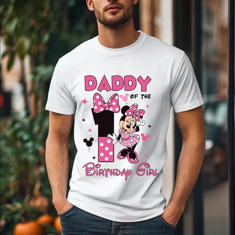 May include: White t-shirt with a graphic featuring Minnie Mouse and the text "DADDY of the BIRTHDAY GIRL". The design includes a large number "1" with pink polka dots, a bow, and stars. The shirt is short-sleeved.