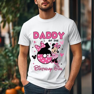 May include: White t-shirt with a graphic design featuring the text "DADDY of the Birthday Girl". The design includes a large number 6 with pink polka dots, a Minnie Mouse character, and pink accents.