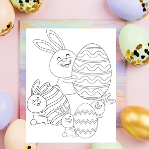 May include: A black and white coloring page featuring four bunnies holding Easter eggs. The bunnies are all smiling and have long ears. The eggs are decorated with stripes and wavy lines.
