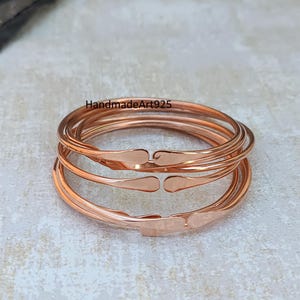 May include: Set of four rose gold stacking bangles. The bangles are smooth and have a hammered finish.