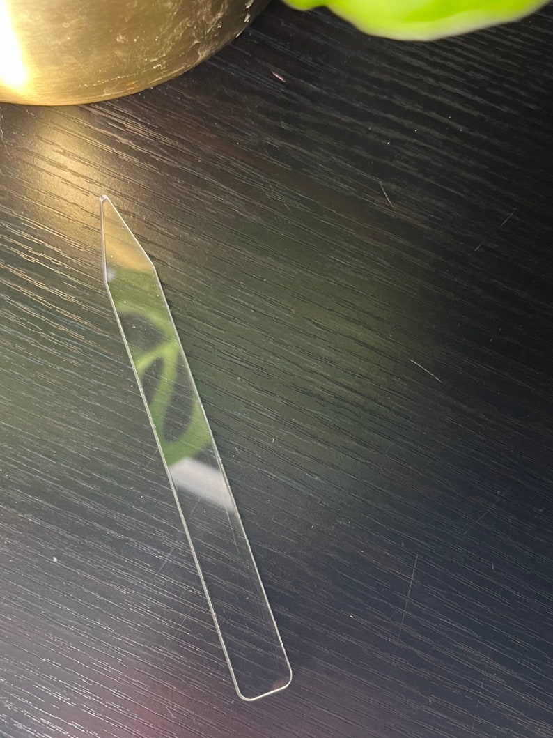 May include: A clear plastic tool with a pointed tip and a rounded end. It is a plant propagation tool used for starting new plants from cuttings.