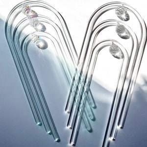 May include: A set of five clear glass arches with crystal prisms hanging from each arch. The arches are arranged in a V-shape.