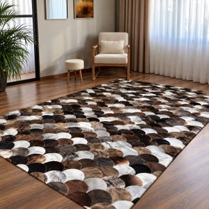 May include: A rectangular area rug featuring a repeating pattern of overlapping circular patches in varying shades of brown, black, white, and gray. The rug is constructed from individual hide pieces arranged in a scalloped, fish-scale design.