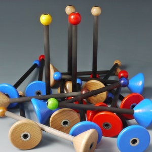 Op de afbeelding: Een verzameling kleurrijke houten speelblokken met blauwe, rode, gele en bruine accenten. De blokken zijn in een willekeurig patroon gerangschikt, waardoor een speels en fantasierijk ontwerp ontstaat.