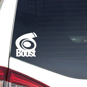 Peut inclure: Autocollant en vinyle blanc avec un graphique de turbocompresseur et le mot "Boost" sur la lunette arrière d'une voiture blanche.