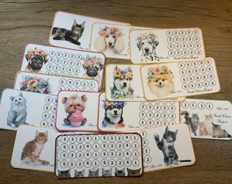 May include: A set of 11 colorful cards featuring various animals, including cats, dogs, and a Yorkshire Terrier. Each card has a different animal illustration and a grid of numbers. The cards are labeled "Save 100" and "Gentle Charm Budgets".