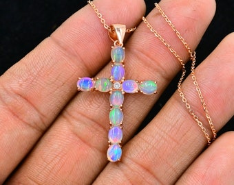 May include: A rose gold chain necklace with a cross pendant. The cross is made of oval-shaped opals with a single clear diamond in the center.