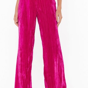 May include: Wide-leg pants in a vibrant pink velvet fabric. The pants have a high waist and a relaxed fit.