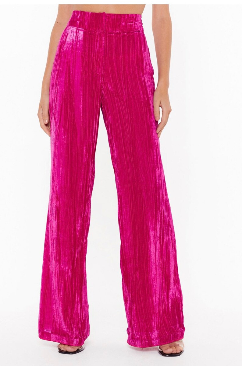 May include: Wide-leg pants in a vibrant pink velvet fabric. The pants have a high waist and a relaxed fit.