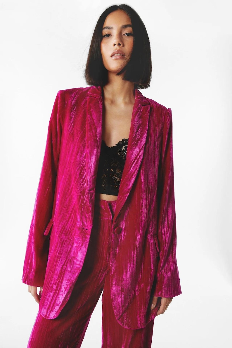 May include: A magenta velvet blazer with a single button closure and a notched lapel. The blazer has a relaxed fit and is made of a soft, luxurious fabric.
