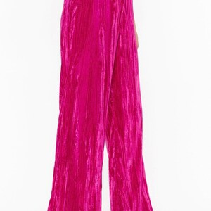 May include: Wide-leg pants in a vibrant pink crushed velvet fabric. The pants have a high waist and a relaxed fit.