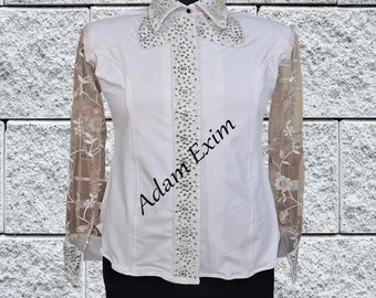May include: White long-sleeve button-up shirt with a sheer lace overlay on the sleeves. The shirt has a row of rhinestones down the front and a rhinestone-embellished collar.