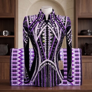 May include: A long-sleeved black show shirt featuring intricate purple and white geometric patterns, heavily embellished with numerous clear and purple crystals. A brown tag labeled BESPOKE hangs from the front, positioned over a purple patterned pad.