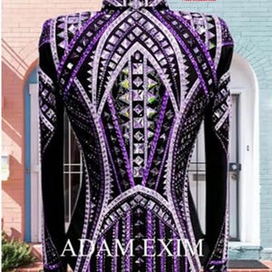 K&ouml;nnte beinhalten: Eine schwarze und violette Showjacke mit geometrischem Muster und Strasssteinen. Die Jacke hat einen wei&szlig;en Besatz und den Text "ADAM EXIM" auf der R&uuml;ckseite.