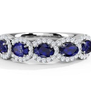 Könnte beinhalten: Ein Silberring mit vier ovalen blauen Saphiren, die in einem Halo aus kleineren Diamanten gefasst sind.