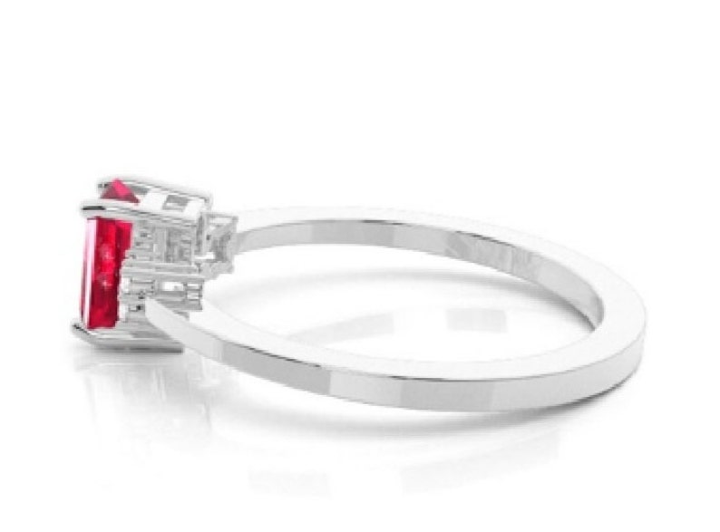 Pu&ograve; includere: Un anello d'argento con una vibrante gemma rossa rettangolare. L'anello ha una fascia in argento lucido e liscio, e la gemma &egrave; incastonata in un'incastonatura dettagliata e sfaccettata. Il design &egrave; elegante e moderno.