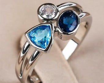 May include: A silver ring with three blue and white gemstones. The ring has a double band design.