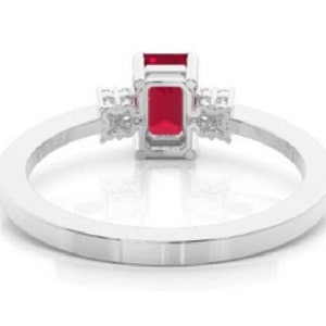 Pu&ograve; includere: Un anello d'argento con una vibrante gemma rossa rettangolare come punto focale. L'anello &egrave; impreziosito da gemme chiare pi&ugrave; piccole su entrambi i lati della pietra principale, incastonate su una fascia lucida ed elegante.